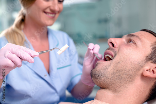 Dentist using dental equipment on men's teeth.