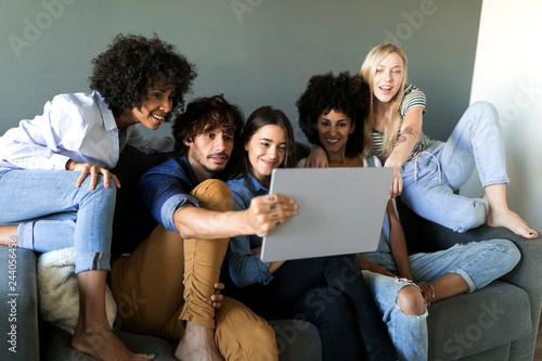 Friends sitting on couch looking at tablet