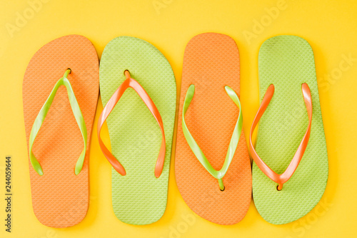 top view of colorful flip flops on yellow background