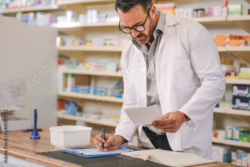 Pharmacist writing prescription pharmacy counter photo