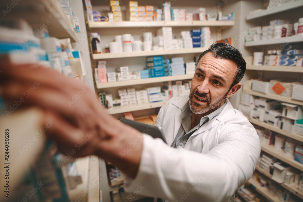 Pharmacy store owner checking stock on shelves Pharmacy store owner checking stock on shelves