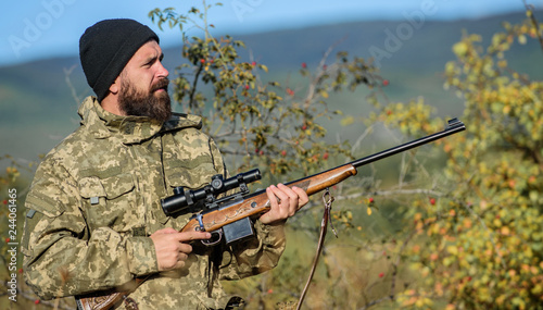 Bearded hunter spend leisure hunting. Hunting equipment for professionals. Hunting is brutal masculine hobby. Man aiming target nature background. Hunter hold rifle. Aiming skills. Hunting permit © be free