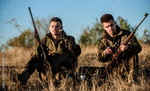 Hunters friends enjoy leisure. Rest for real men concept. Hunters with rifles relaxing in nature environment. Hunting with friends hobby leisure. Hunters satisfied with catch drink warming beverage