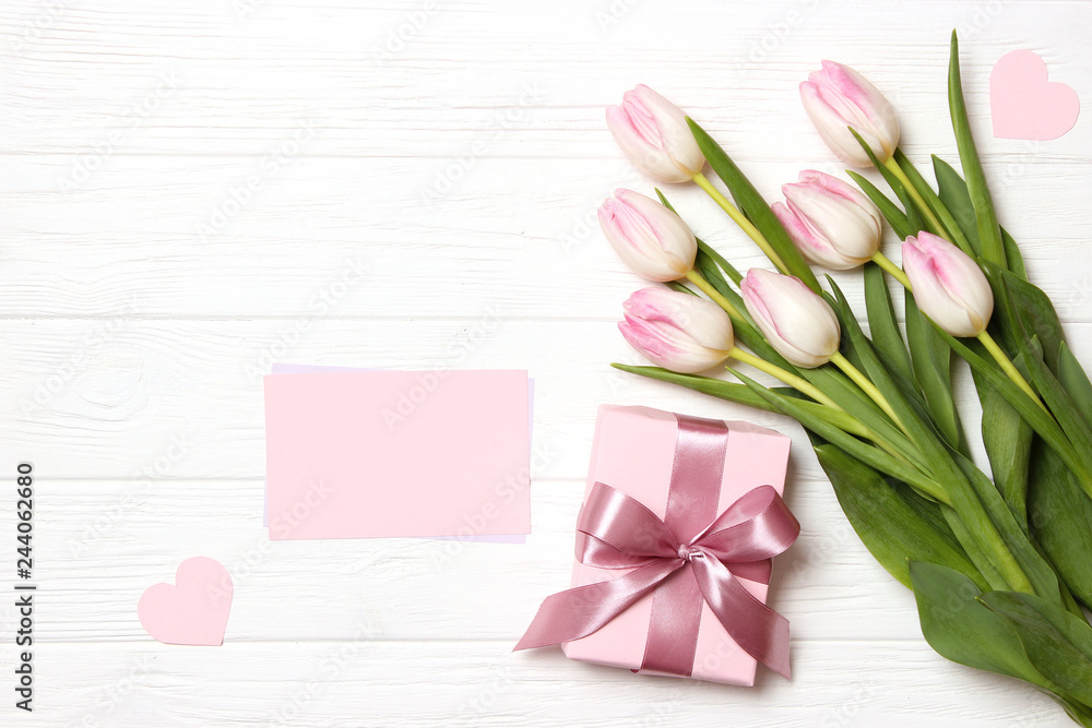 Fototapeta premium beautiful tulips bouquet, gift and card for text on wooden background top view. Mother's Day Background, International Women's Day, Birthday. Holiday, give a gift.