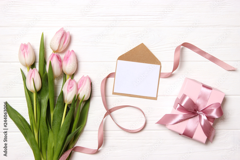 Fototapeta premium beautiful tulips bouquet, gift and card for text on wooden background top view. Mother's Day Background, International Women's Day, Birthday. Holiday, give a gift.