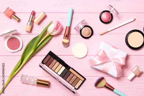 makeup products and beautiful spring flowers on wooden background. Top view.
