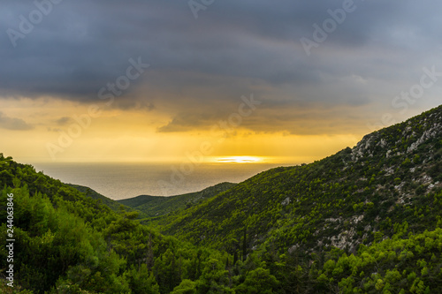 Greece, Zakynthos, Spectacular orange burning dramatic sky and beautiful green valley to the ocean