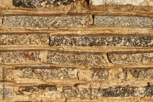 Fragment of a wall of small granite blocks. On the wall a thin layer of water flows. Background