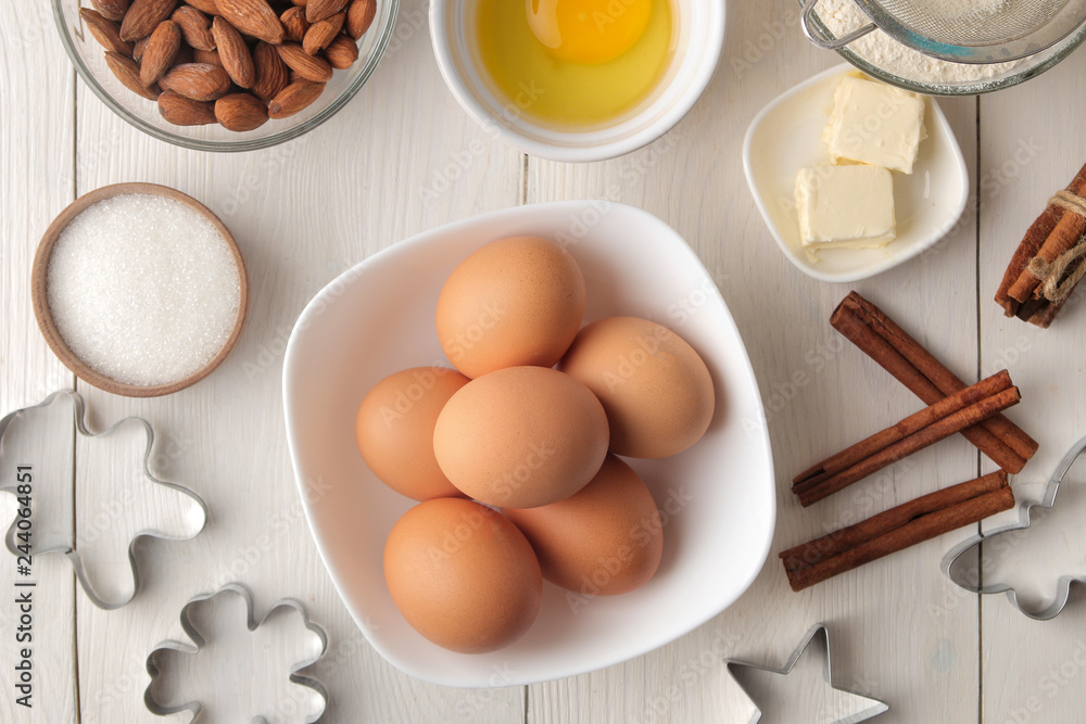 baking ingredients. baking tools. butter, eggs, sugar, milk, cinnamon, almonds on a white wooden background. view from above baking ingredients. baking tools. butter, eggs, sugar, milk, cinnamon, almonds on a white wooden background. view from above