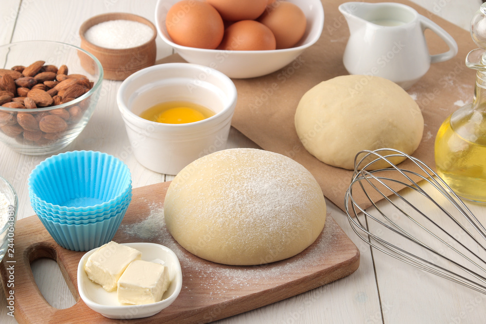 baking ingredients. baking tools. dough and butter, eggs, sugar, milk, cinnamon, almonds on a white wooden background baking ingredients. baking tools. dough and butter, eggs, sugar, milk, cinnamon, almonds on a white wooden background