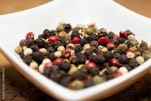 Peppercorns laying in white porcelain container