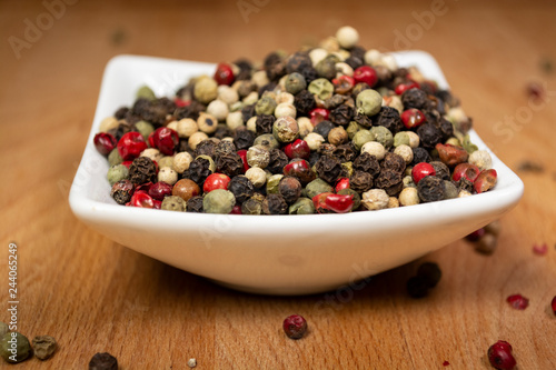 Peppercorns laying in white porcelain container