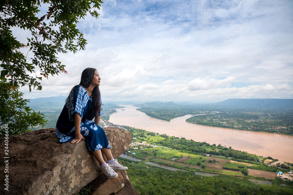 Naklejka premium Young woman sitting on a mountain top
