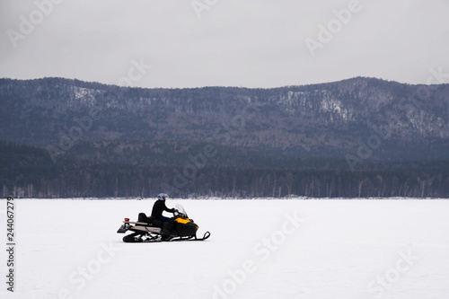 a man rides on a vehicle on the ice against the mountains. sports, recreation.