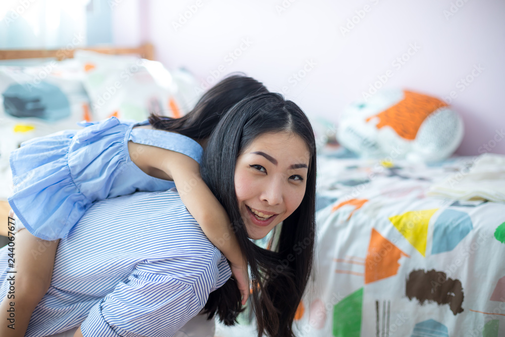 Asian girl on the back of her mother in the house