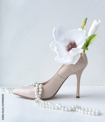 1 white stiletto Shoe, pearl necklace, Magnolia flower on white background, women's holiday photo