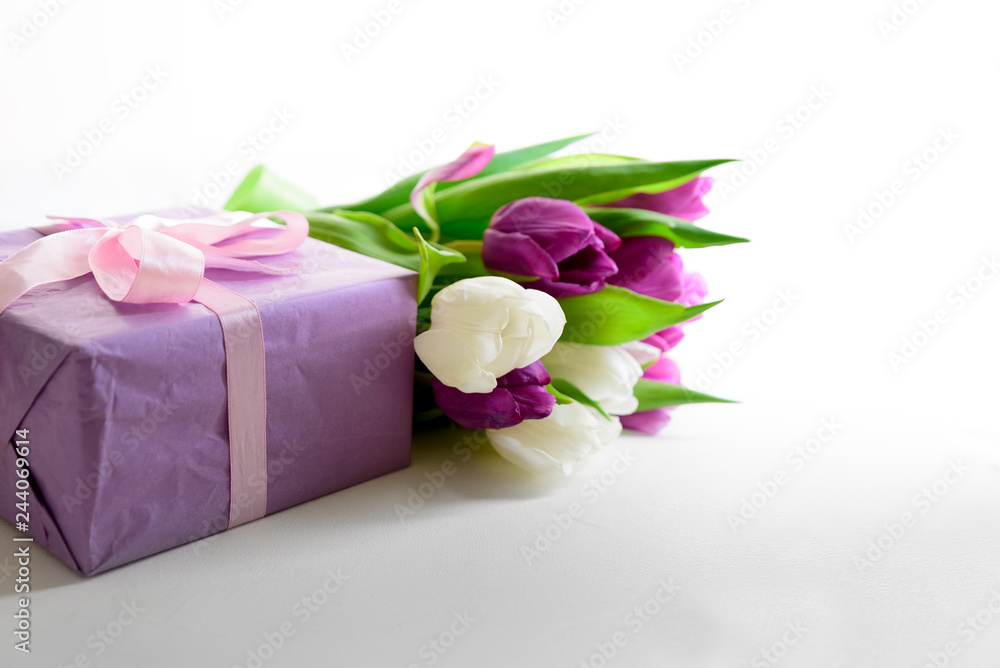 Bouquet of white and purple tulips and gift box on white wooden background. Top view. Flat lay. Copy space. Valentines day, mothers day, birthday, wedding celebration concept.