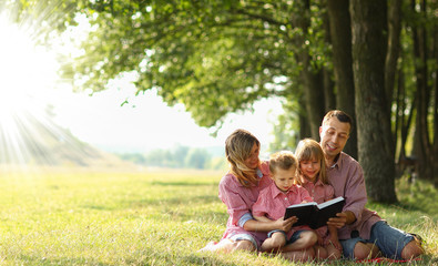 Young family reading the Bible in nature
