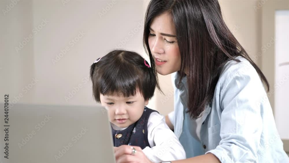 Asian Mother and daughter 5 years old using laptop computer together at home. Education and Technology concept Slow Motion Asian Mother and daughter 5 years old using laptop computer together at home. Education and Technology concept Slow Motion