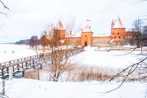 Medieval castle of Trakai, Vilnius, Lithuania, Eastern Europe, located between beautiful lakes and nature with wooden bridge in winter, with frozen lake and snow