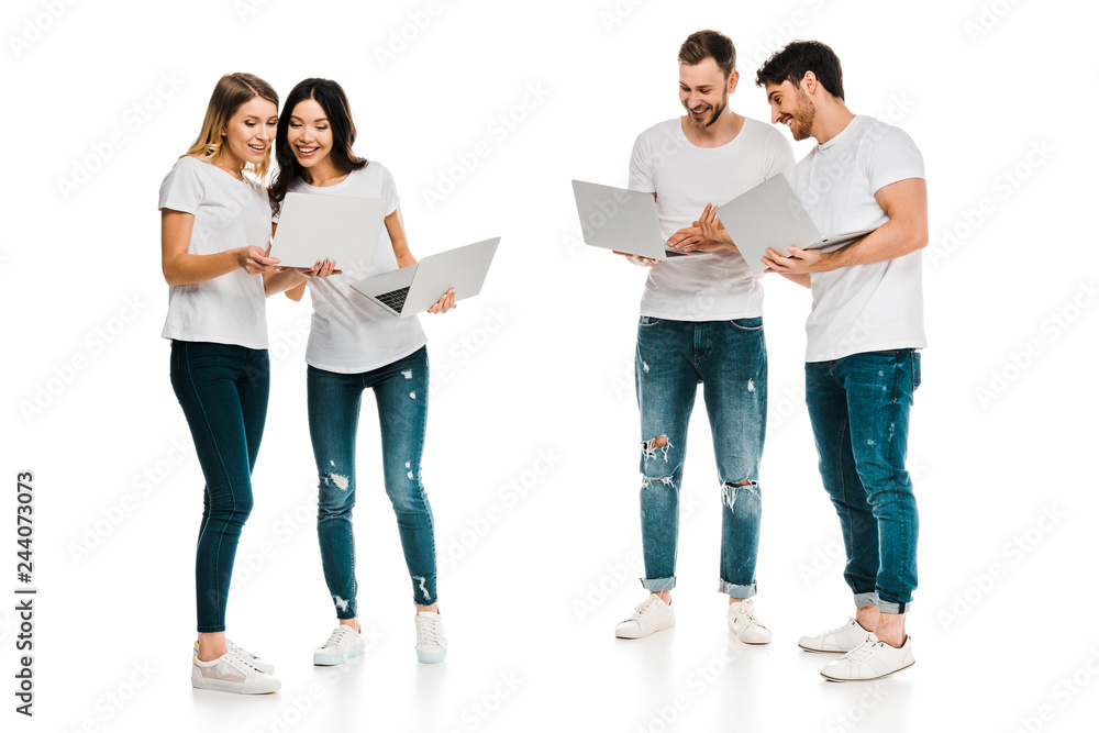 smiling young men and women standing together and using laptops isolated on white