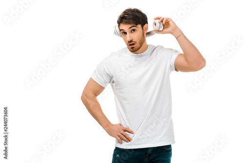 young man with open mouth holding headphones and looking at camera isolated on white