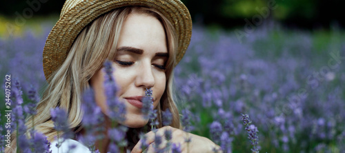 Blonde girl in a straw hat in a lavender field, closing her eyes inhales the scent of flowers