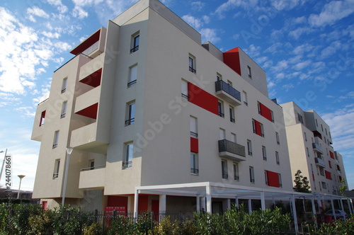 Bâtiment moderne blanc et rouge et ciel bleu dans un lotissement d'une ville de France 