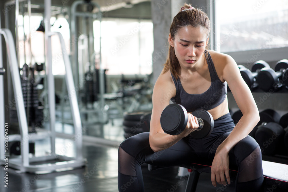 Fitness woman in sport wear pumping up muscules with dumbbells on bench in gym. girl exercises lifting dumbbell .bodybuilder.workout Fitness woman in sport wear pumping up muscules with dumbbells on bench in gym. girl exercises lifting dumbbell .bodybuilder.workout