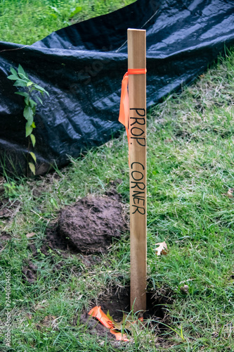 Obraz na plátně Closeup of wooden stake in ground with orange tape and Property Corner marked on
