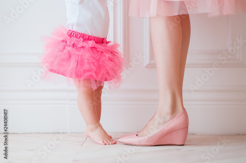  Mother's legs and daughters in pink skirts. My daughter is trying to put her legs to her mother. Legs girls and women. mother holds daughter in her arms