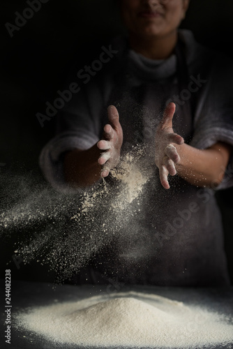 Midsection of baker dusting flour on kitchen countertop photo