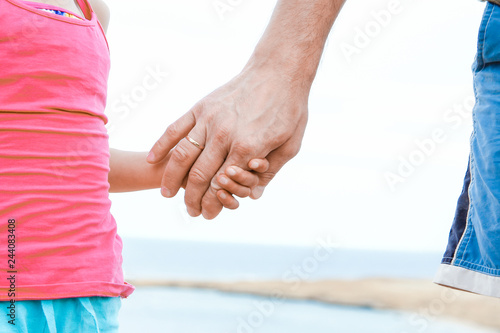 Beautiful hands of parent and child on sea background