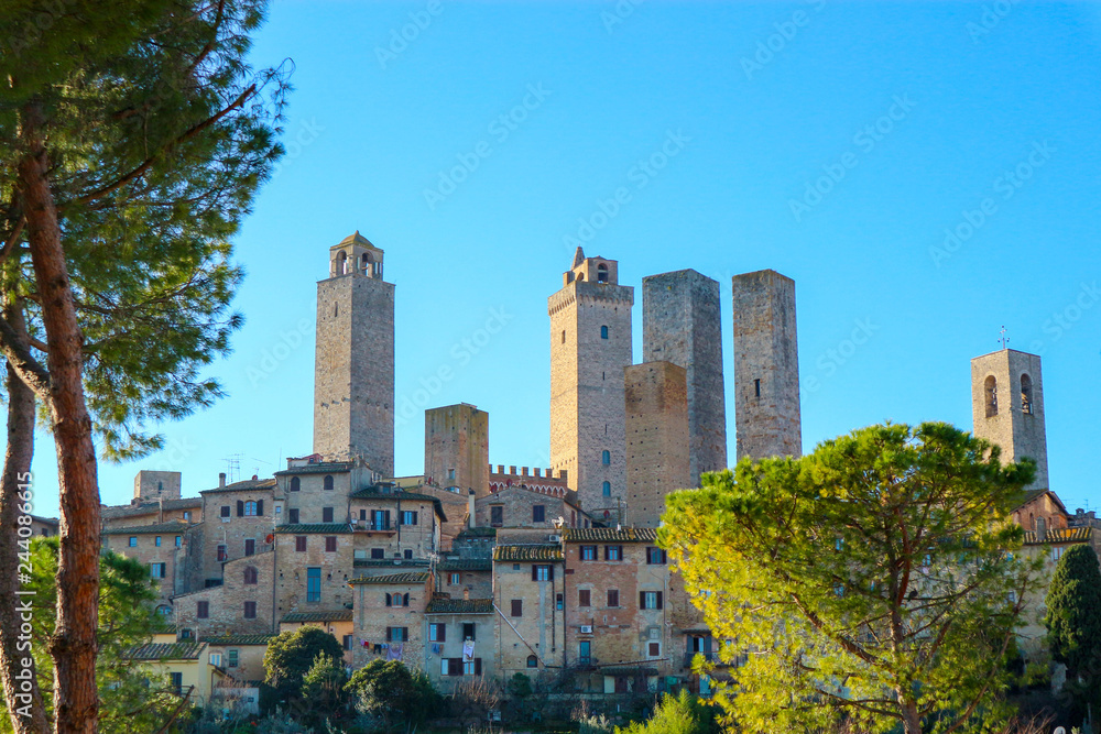 Famous San Gimignano medieval tower with a trees and blue sky on the background, Tuscany, Italy
