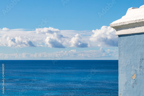 Looking out over the ocean, with part of a blue and white building in the foreground © lemanieh