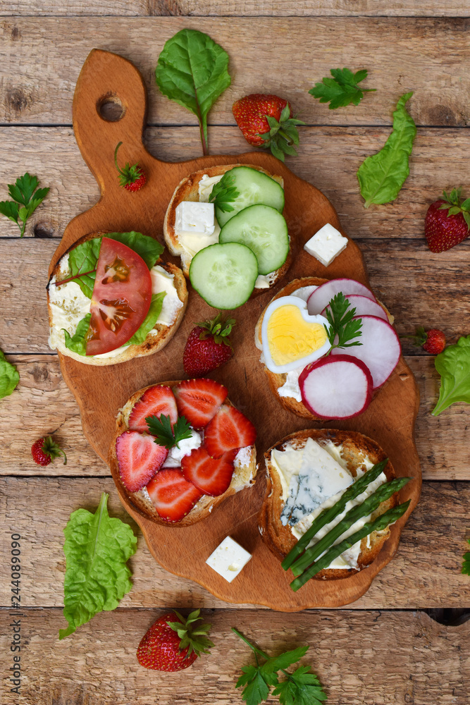 Set of healthy whole wheat bread sandwiches with fuits, vegetables, cheese and leafy green herbs on picnic wooden table. Ciabatta sandwich bar. Top view. Lunch time snacks concept. Vegetarian food Set of healthy whole wheat bread sandwiches with fuits, vegetables, cheese and leafy green herbs on picnic wooden table. Ciabatta sandwich bar. Top view. Lunch time snacks concept. Vegetarian food