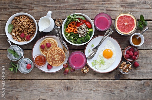 Brunch or breakfast table. Festive brunch set  meal variety with quinoa salad bowl  fried egg  granola  pankes  chia seeds pudding and smoothy  . Overhead view