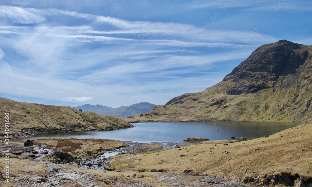 Mountain tarn and cliff on sunny day