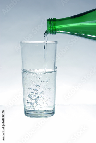 Mineral water pours from the bottle into the glass