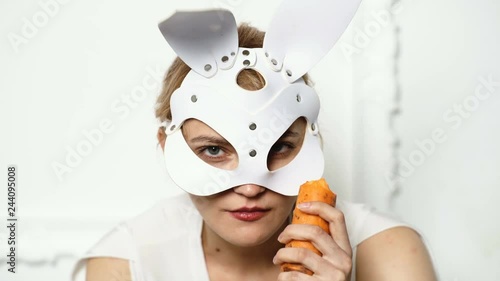 Hot sexy girl in leather mask on white background. Close up easter bunny girl eat carrot isolated on white background. Happy easter days. photo