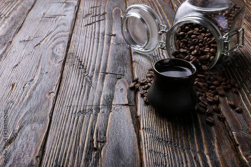 An authentic cup of strong coffee and a jar of coffee beans and poured grains. Copy space.