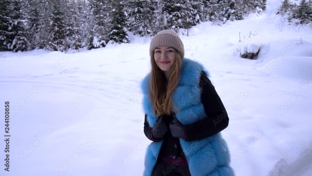 Young beautiful girl alone in the winter forest. She is looking at the camera. The girl smiles and flirts. She's happy. Slow motion. Young beautiful girl alone in the winter forest. She is looking at the camera. The girl smiles and flirts. She's happy. Slow motion.