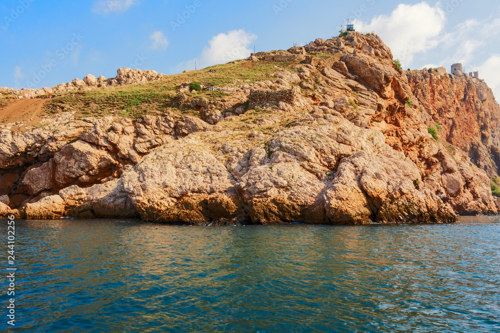 landscape with a beautiful and powerful cliff, with fishermen and tourists on the black sea in the Crimea