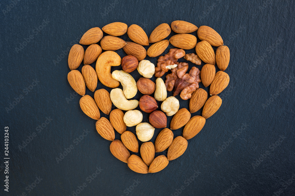 Assorted nuts heart shaped on dark background. Assorted nuts heart shaped on dark background.