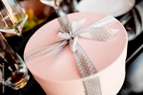 Round pink gift box with a speckled bow on the wedding table