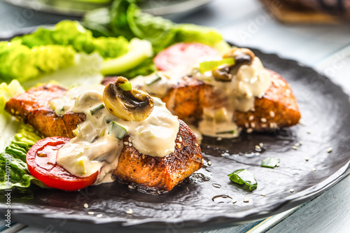 Delicious grilled roasted salmon fillets or steaks with mushroom sauce sesame tomatoes and lettuce salad