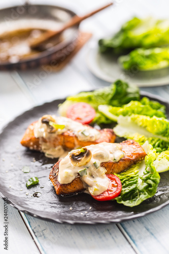 Delicious grilled roasted salmon fillets or steaks with mushroom sauce sesame tomatoes and lettuce salad