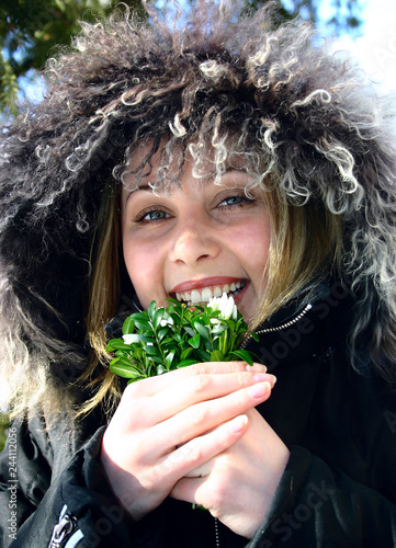 Young, beautiful girl in a hood, with the first spring snowboys photo