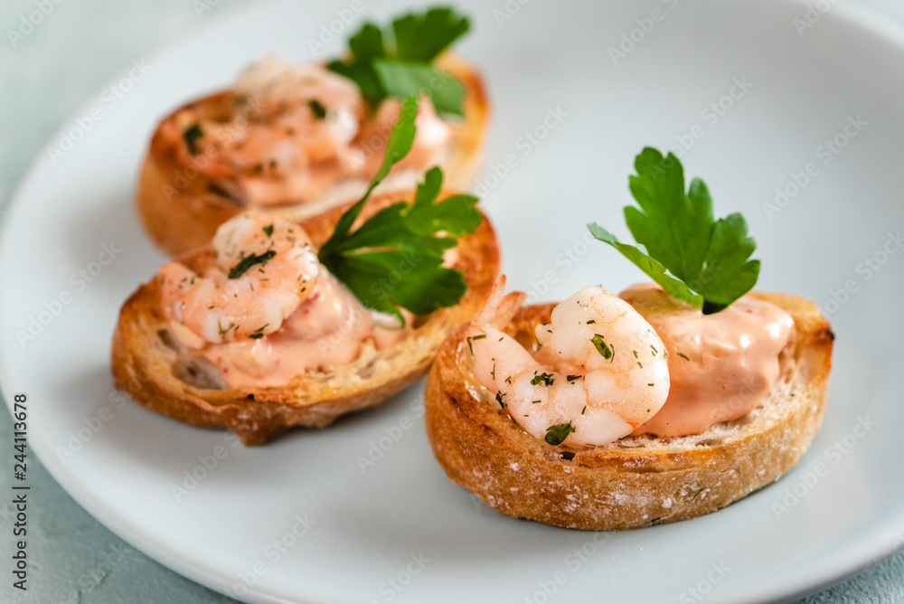Bruschetta sandwiches with shrimps, creamy sauce and parsley.
