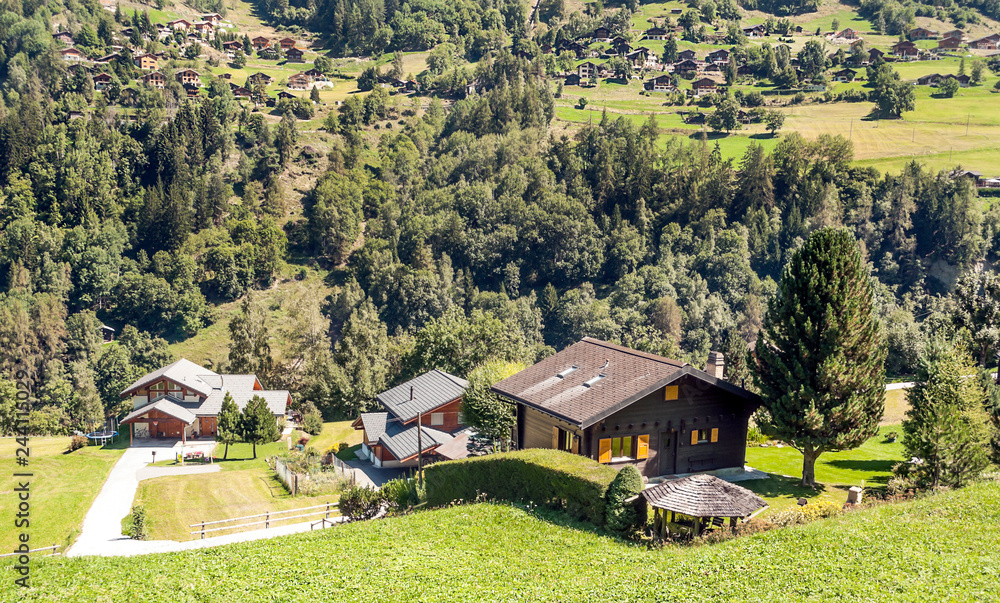 Wooden houses in the meadows of the Swiss Alps in the Saint Luc valley on a sunny day.